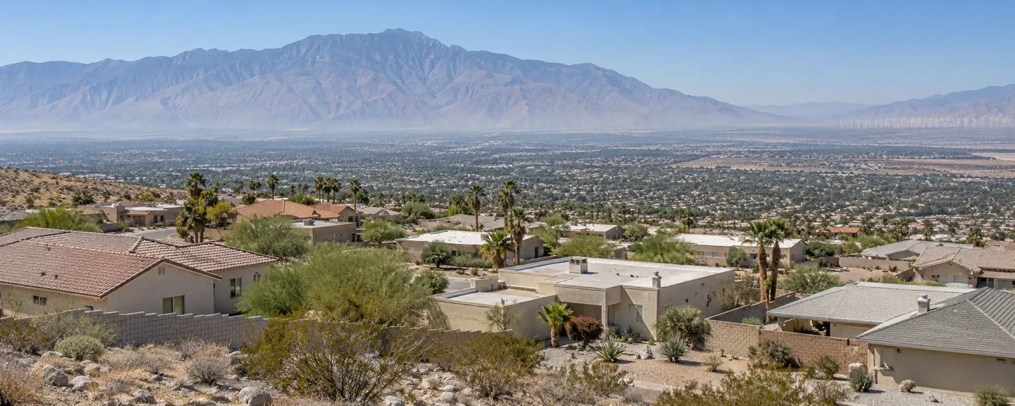 Illustrative view from the hillside over homes with tile and flat roofs, the valley spread out below and Mount San Jacinto across it