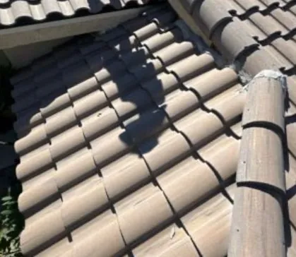 Barrel tile courses on a roof slope beside a ridge cap, the shadow of the roofline falling across them