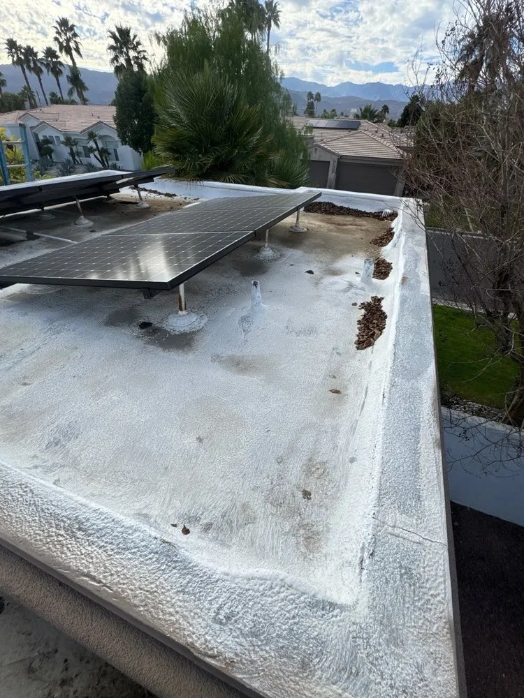 Before: a flat roof with a weathered, stained surface and leaf debris along the edge, a solar panel on stands