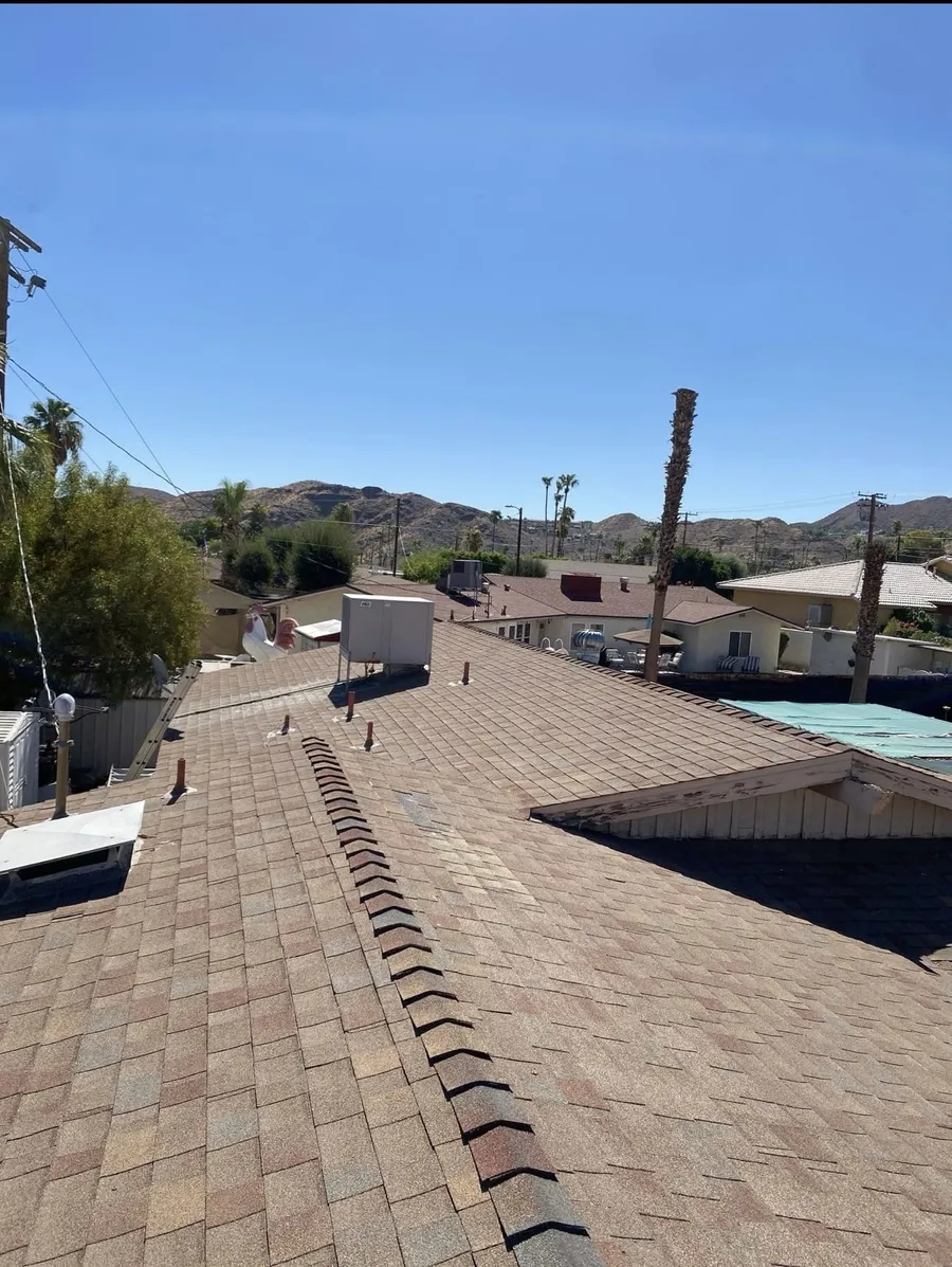A brown shingle roof with barrel ridge tiles running along the peak, desert homes beyond